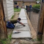 worker filling the cement on the walkway leading to the door