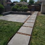 concrete walkway bordered by gravel and patches of green grass