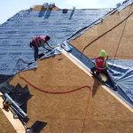 workers covering the roof with tarp