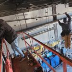 workers are installing or repairing overhead utilities in a garage