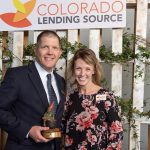 man and woman posing for a photo while holding a trophy