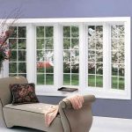 lounge chair beside a bay window overlooking a lush garden with trees