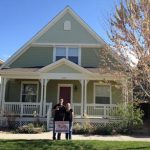 male and female standing in front of a small house