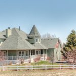 large house with wrap-around porch and split-rail fence