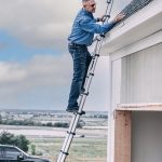 man stepping on a stair to check the house roof
