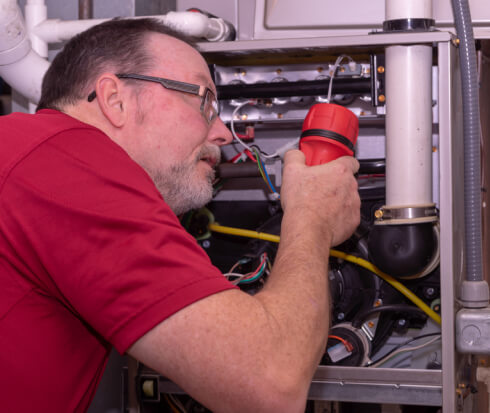 HVAC tech checking gas furnace for repair