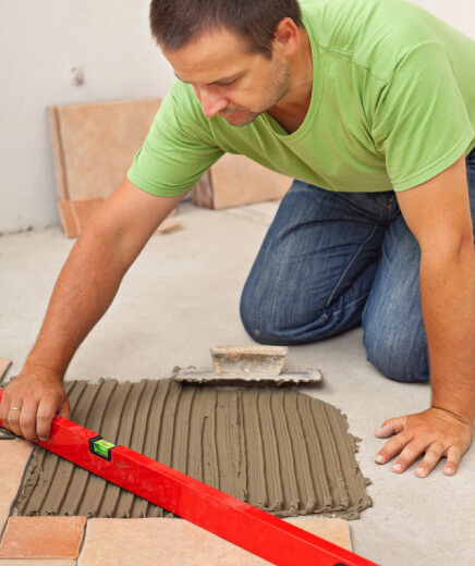 worker checking floor with a level before installing ceramic tiles