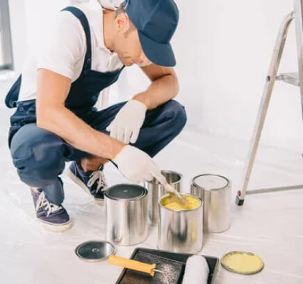 Interior Painter mixing the paint in cans