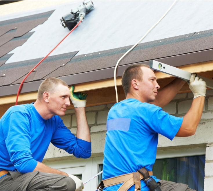 Two roofing workers using water level balance meter before roof installation