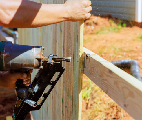 Fence installer using air nail gun to install wooden fence