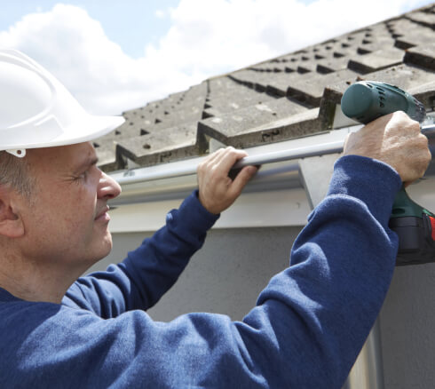 Worker replacing gutter of a house