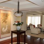 flower vase placed on top of a wooden table, almost near hanging light