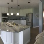 A modern kitchen featuring granite countertops and white cabinets