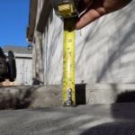 person measuring concrete floor height using industrial tape
