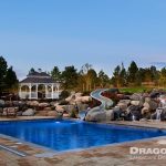 large pool with stone poolscape and slide near gazebo