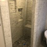 A modern bathroom shower with a tiled interior and a glass enclosure.