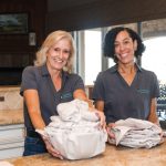 two women smiling in Checkmate Moving and Storage shirt