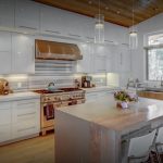 modern kitchen filled with white cabinets and stainless appliances