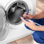 person writing on paper while checking frontload washer